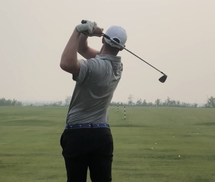 Canadian professional golfer Jake Thomas completing an iron shot on the practice range